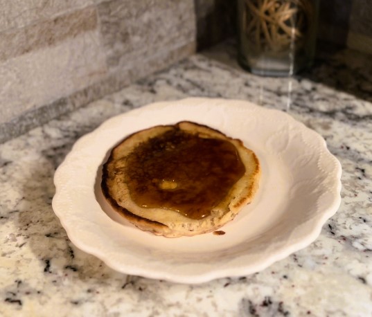 Apple butter sourdough pancakes on white plate with butter and maple syrup