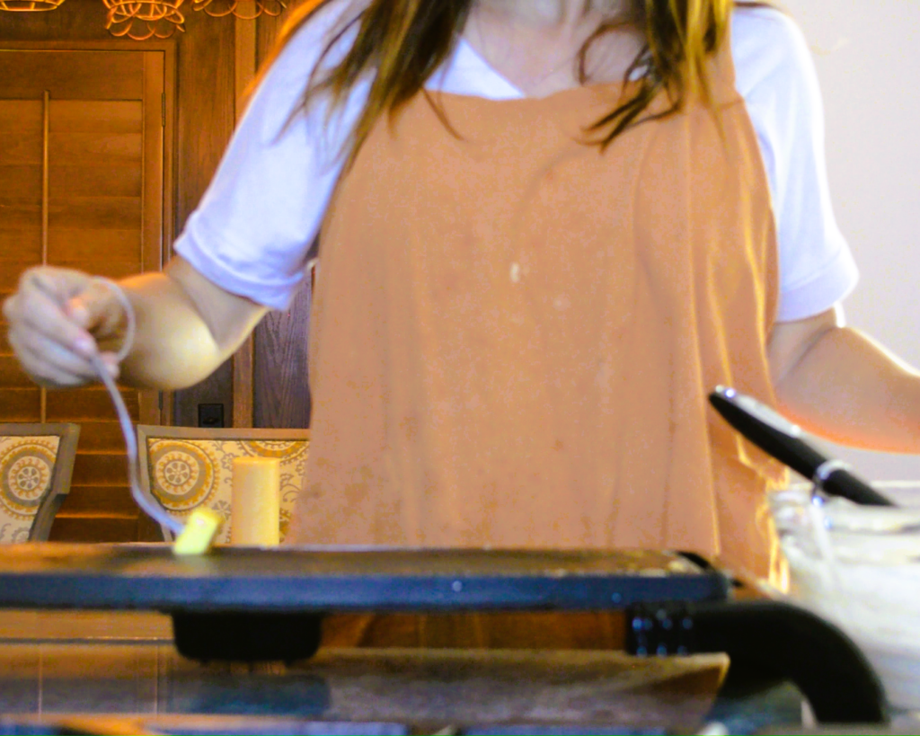 woman coating a skillet with with butter using a fork