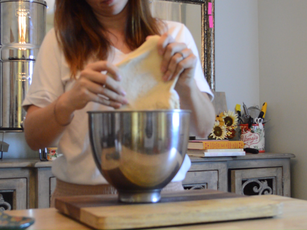 woman Stretching bacon maple cinnamon rolls dough in metal bowl