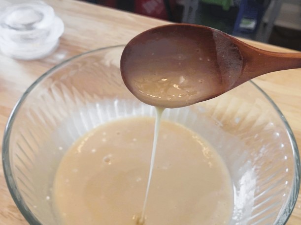 wooden spoon stirring icing in glass bowl