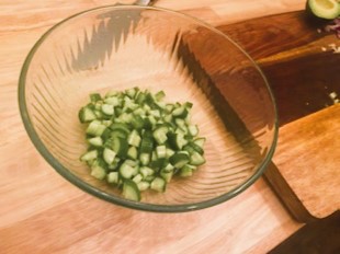 diced cucumbers in glass bowl on cutting board