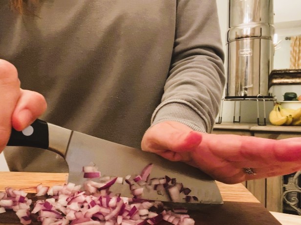 woman dicing red onion with knife