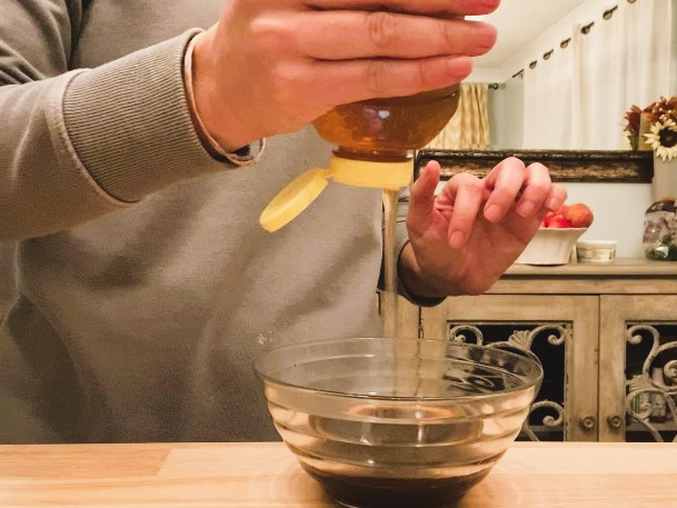 woman pouring honey into glass bowl