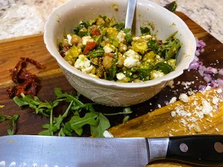 Mediterranean couscous salad in white bowl on cutting board