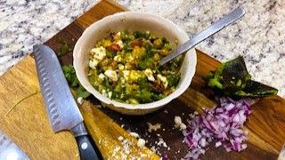 Mediterranean couscous salad in white bowl on cutting board beside knife